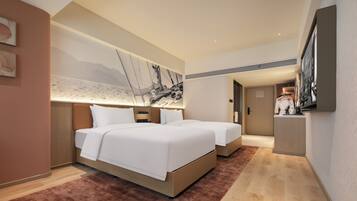 Quarto de hotel moderno com uma cama grande, uma escrivaninha e uma pintura de veleiros.
