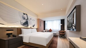 Una habitación de hotel moderna con una cama grande, un escritorio y una televisión.