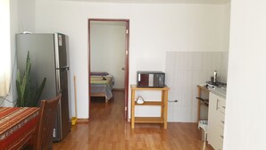 Un ambiente compatto con angolo cottura, un letto, un frigorifero e zona pranzo.