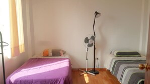 Una camera da letto con un letto, una ventola da terra e una porta.