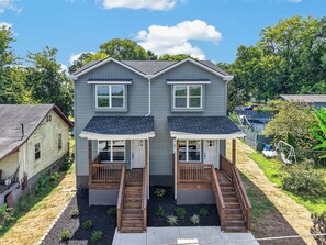 A two-story residential building with a front porch, wooden stairs, and a small garden area. - Johnston #A New 3b Home Near Downtown Knoxville (Knoxville)