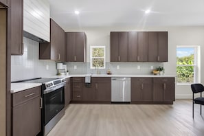 A modern kitchen with dark wood cabinets, a stainless steel range, and a dishwasher. - Johnston #A New 3b Home Near Downtown Knoxville (Knoxville)