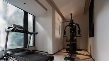 A home gym with a treadmill and weightlifting equipment.
