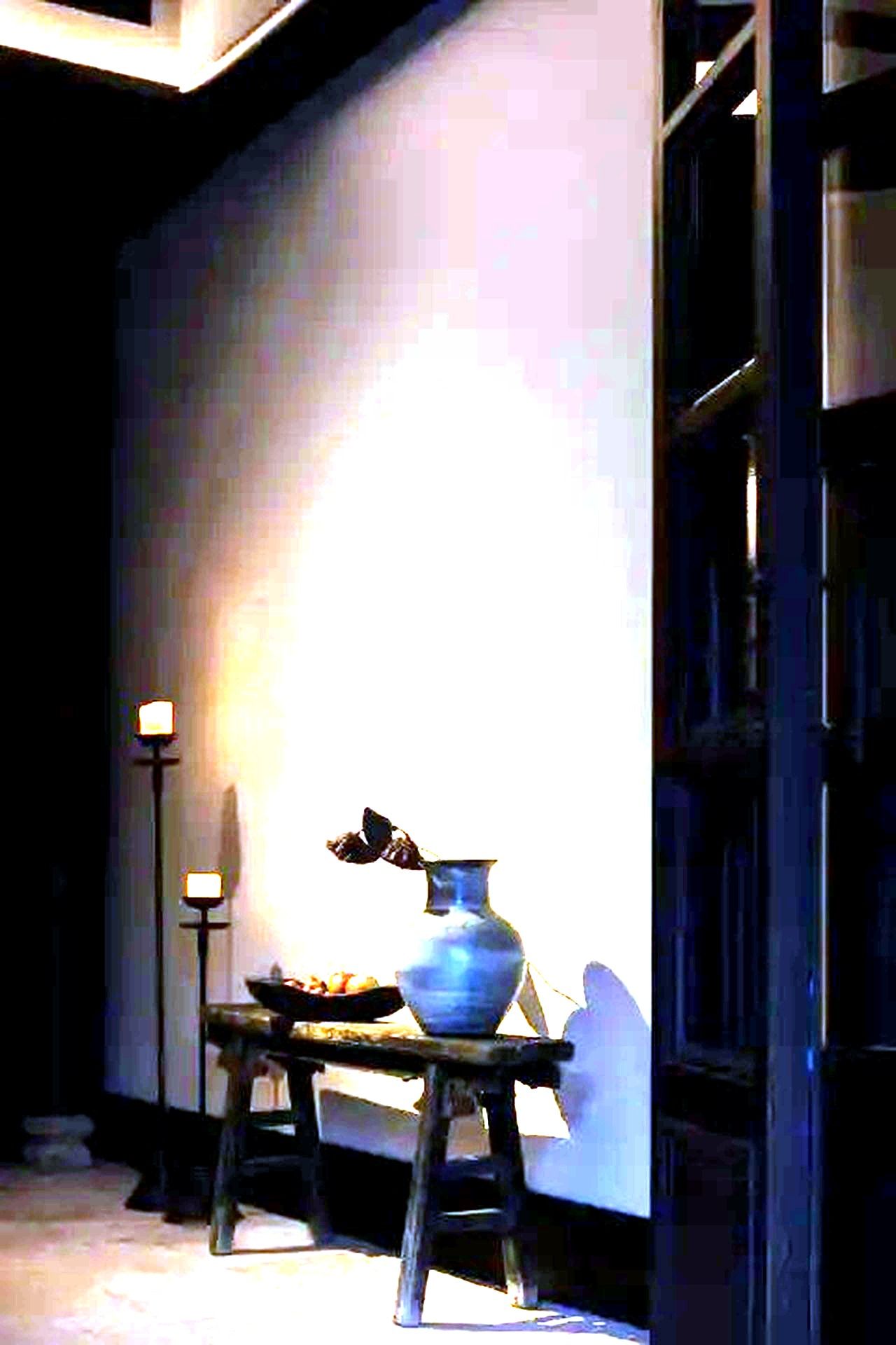 A room with a table holding a vase and a lamp.