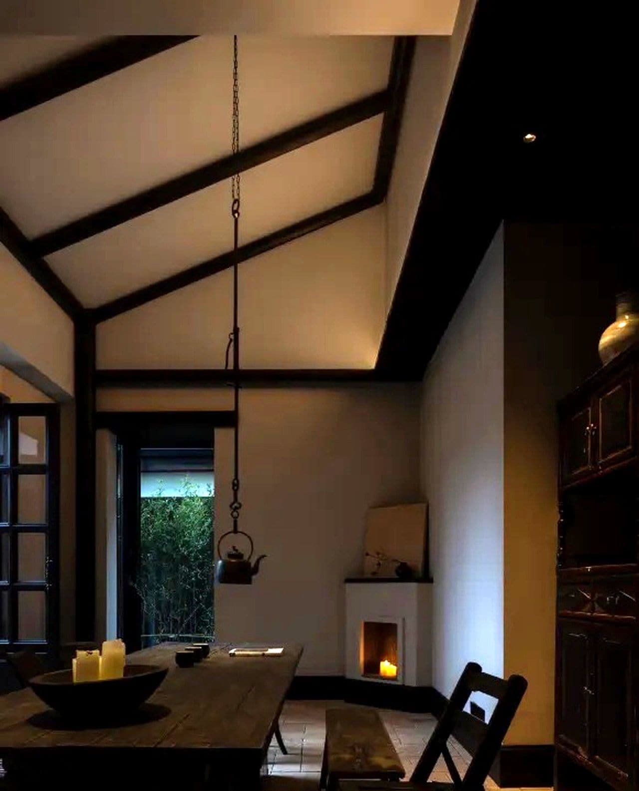 A dining area with a table, chairs, a hanging light fixture, and a fireplace.