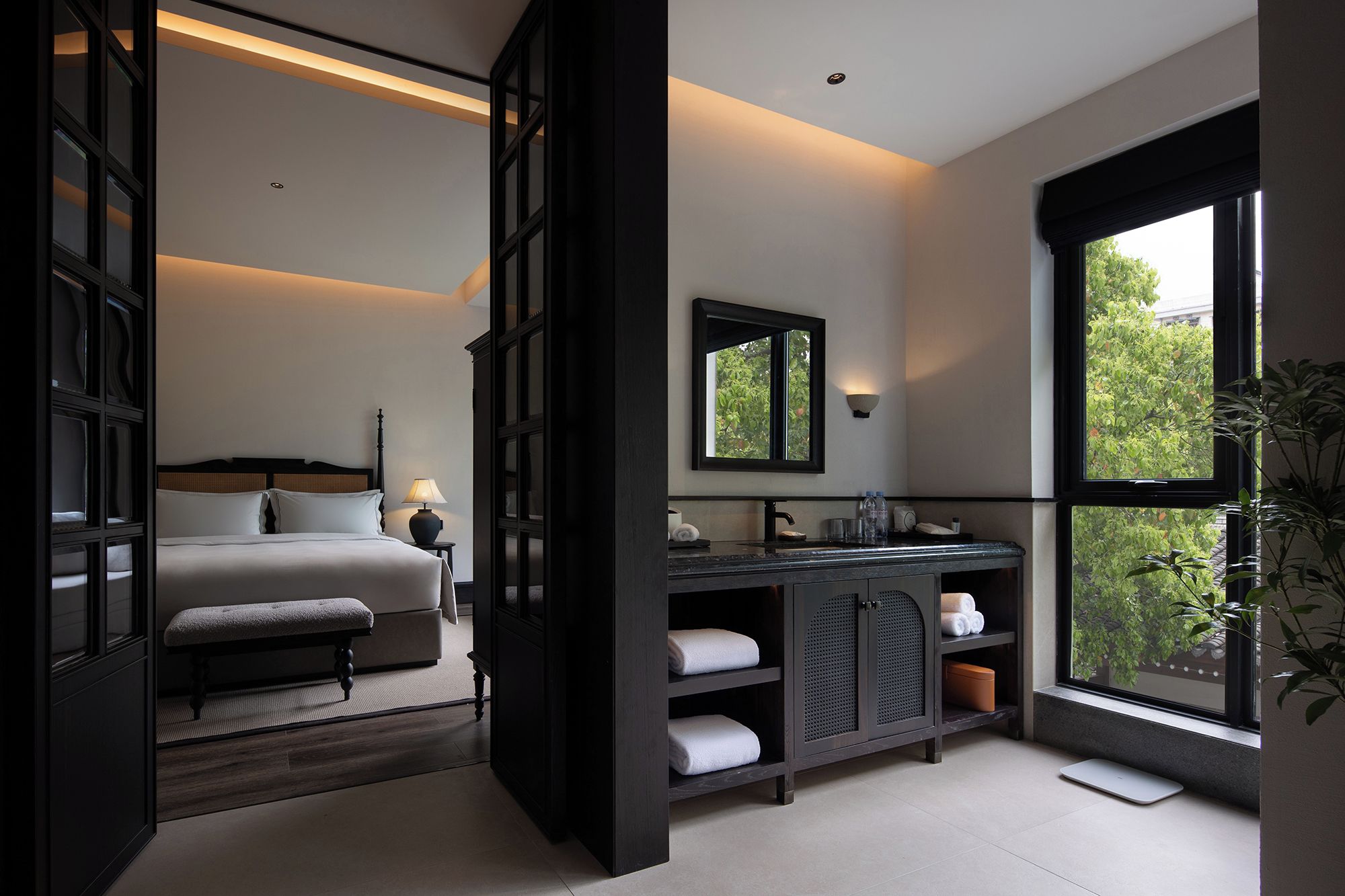 A modern bedroom with a bed, bedside table, and a large window.