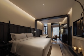Una habitació d'hotel amb un llit gran, taules de nit, escriptori, cadira, armari i mirall.