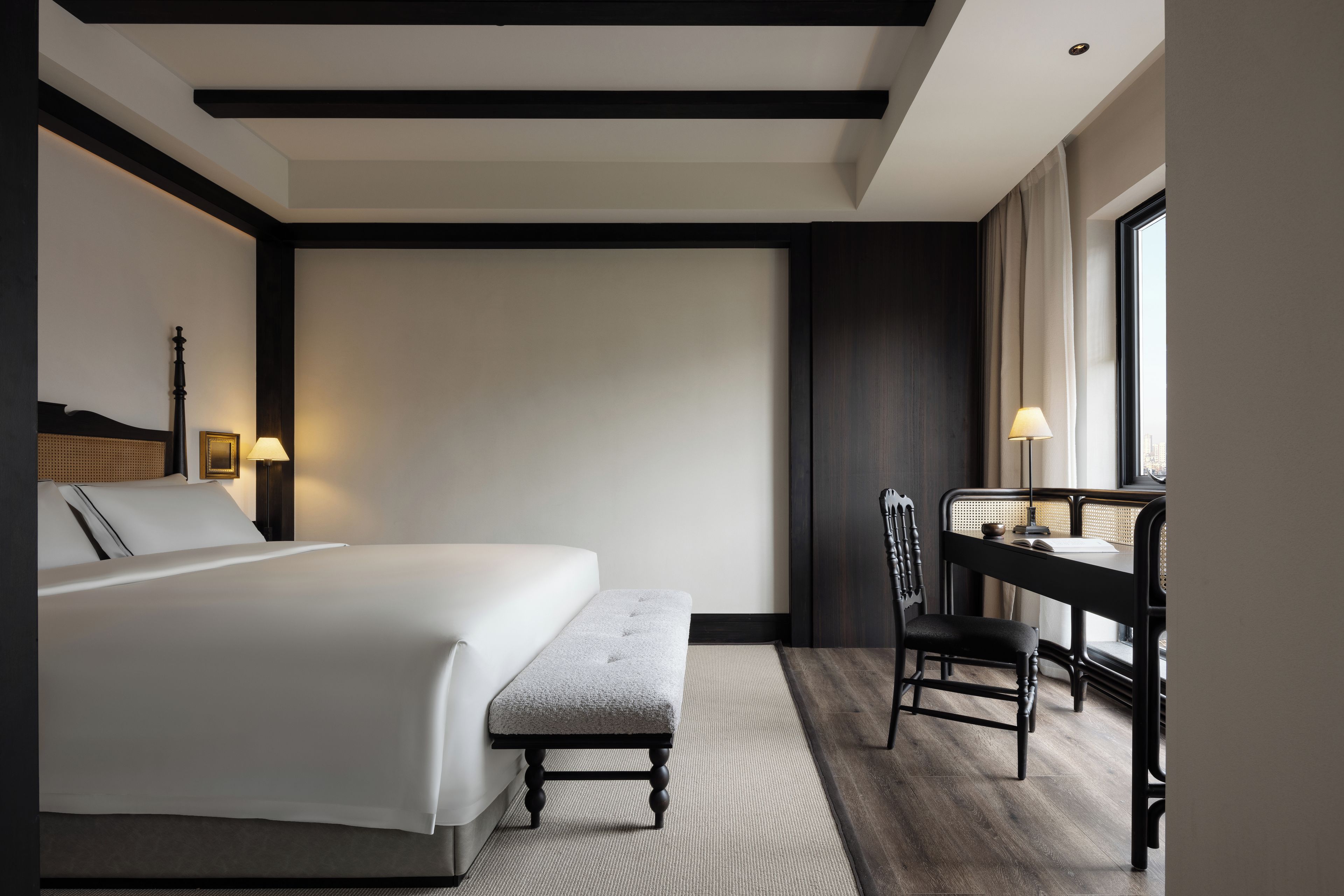 Una camera d'albergo con un letto, una scrivania, una sedia e una finestra.