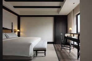 A hotel room with a bed, a desk, a chair, and a window.