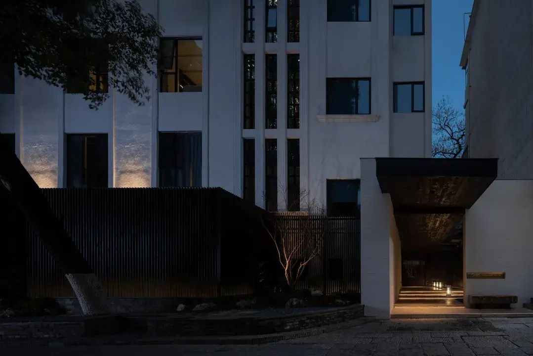Um edifício moderno com fachada plana, grandes janelas e entrada bem iluminada.