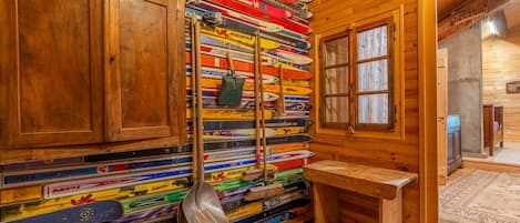 Una habitación con paredes de madera, un banco de madera y un mueble en la pared con varios esquíes.
