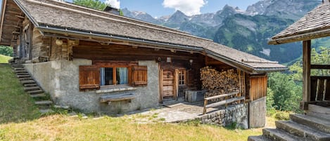 Une cabane de montagne rustique, avec des fondations en pierre, un revêtement extérieur en bois et un toit à forte pente.