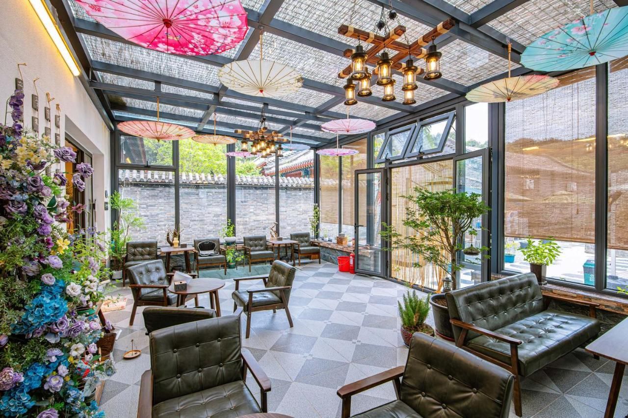 Un vaste espace intérieur aménagé avec de nombreux coins salon, de grandes fenêtres et des parasols décoratifs.