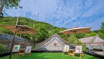 An outdoor area with a traditional building, green lawn, and umbrellas.