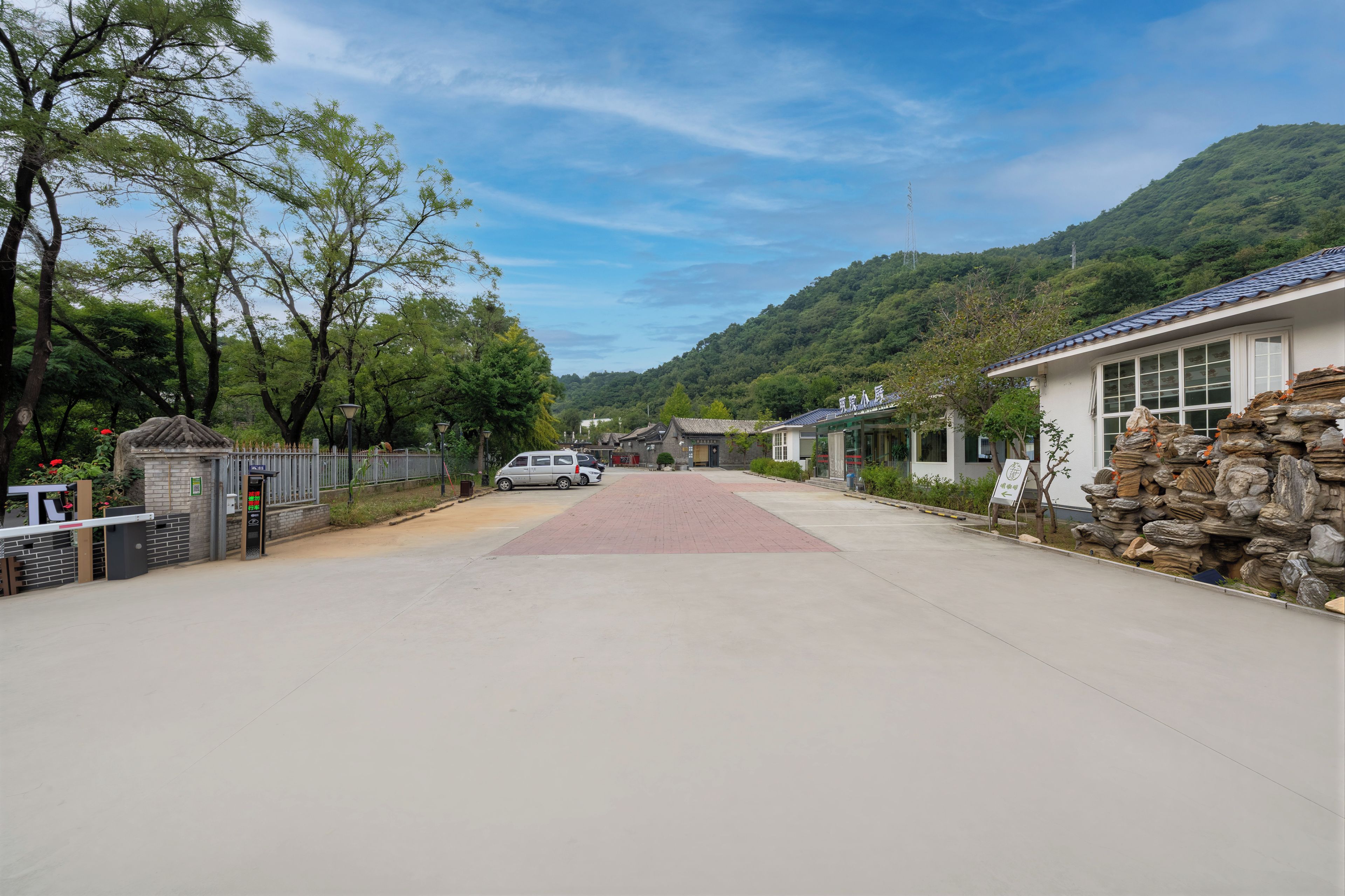 A street view with a paved road, a parked car, and buildings with traditional architecture.