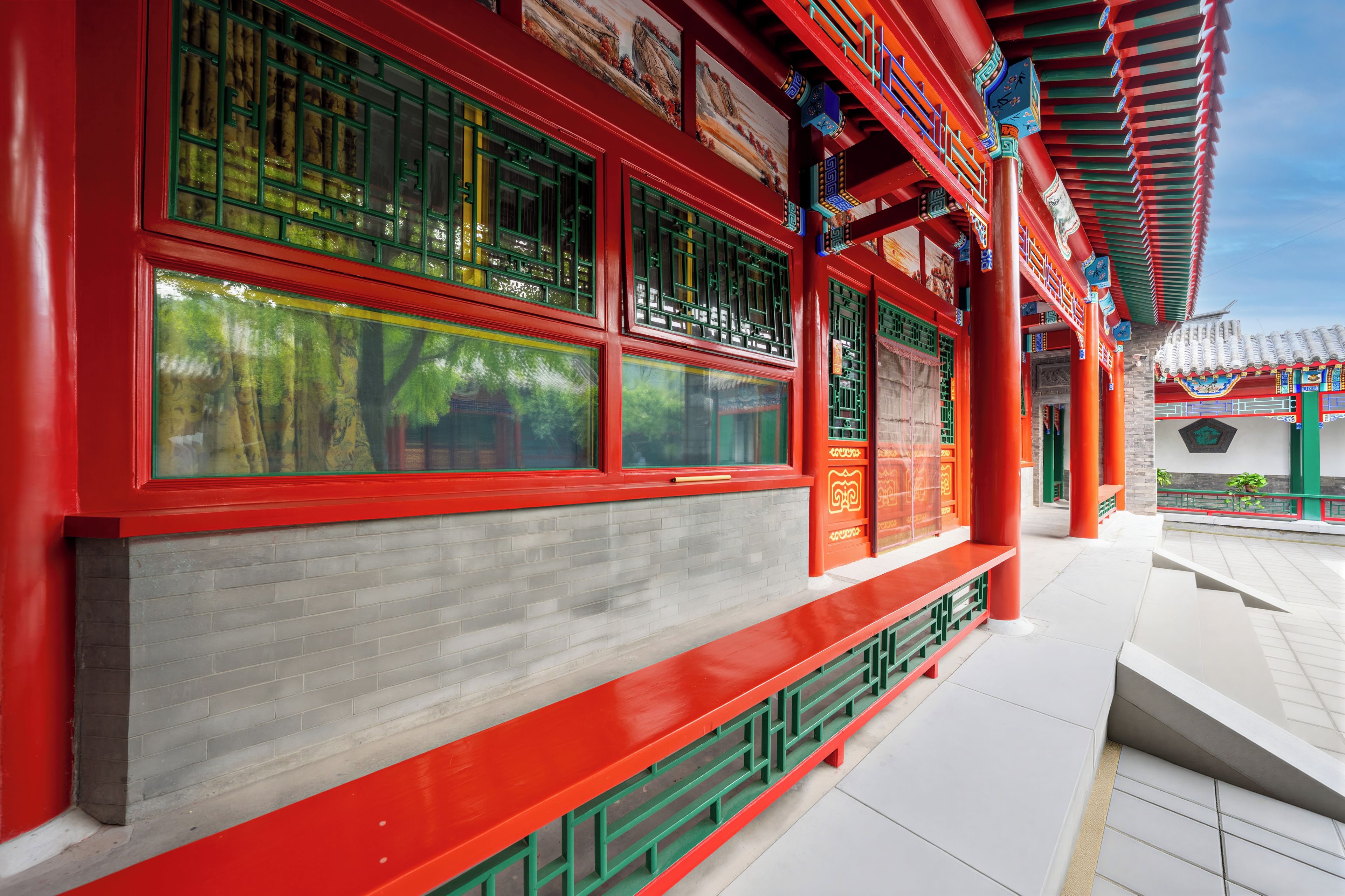A traditional building with red and green architectural elements, including windows with intricate designs and a tiled roof.