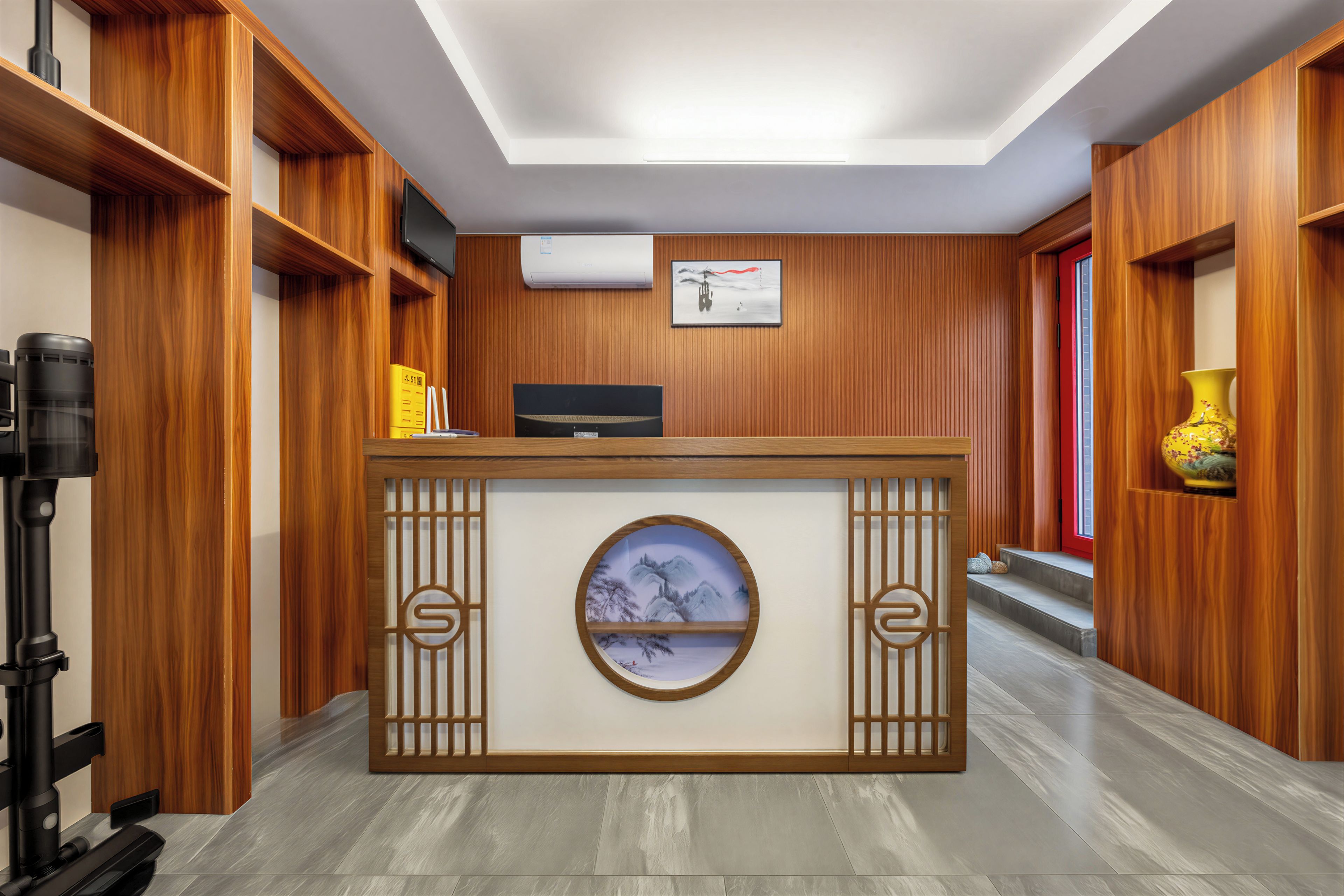 Un mostrador de recepción con un televisor de pantalla plana, un aire acondicionado instalado y una obra de arte enmarcada encima.