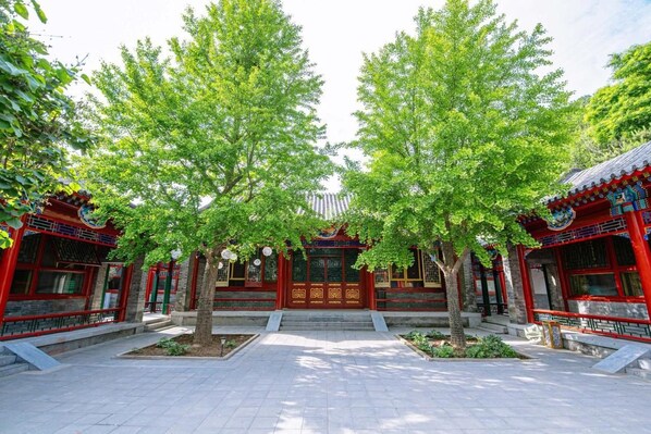 A traditional building with a central entrance flanked by trees, surrounded by red and blue architectural details.