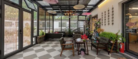 A spacious room with a checkered floor, large windows, and a seating area with chairs and a table.