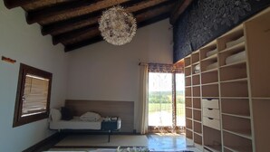 Une pièce comprenant un lit, une fenêtre avec des stores, un luminaire au plafond et un meuble de rangement intégré.
