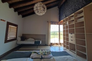 A room with a bed, a window with blinds, a ceiling light fixture, and a built-in storage unit.