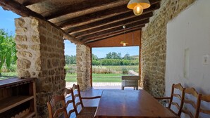 Un coin repas rustique, avec une table et des chaises en bois, des murs en pierre et une vue sur un paysage verdoyant.