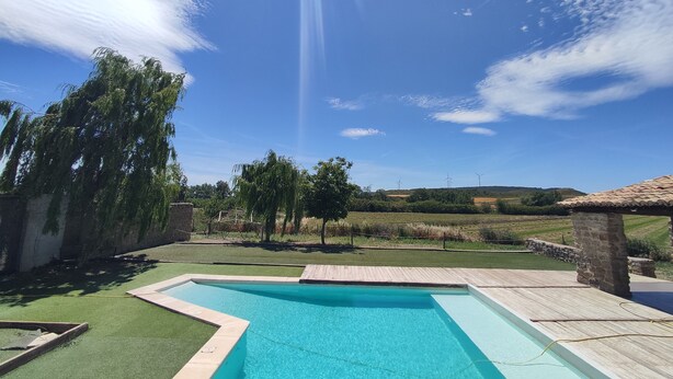 Une piscine, avec un ciel bleu dégagé et des éoliennes visibles au loin.
