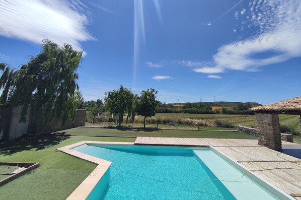 A swimming pool with a clear blue sky and distant wind turbines.