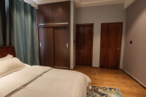 A bedroom with a bed, a wardrobe, and two doors. - 2 Bedroom Apartment with full Kitchen, Accra 3B (Ga North Municipal)