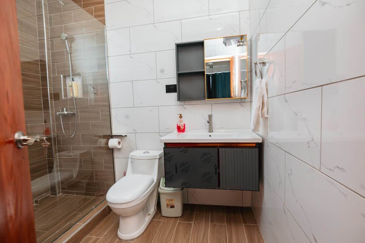 A bathroom with a toilet, sink, mirror, and shower.