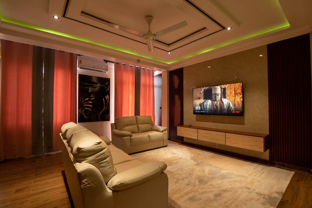A modern living room with a flat-screen TV mounted on the wall, a ceiling fan, and a seating area with two sofas.