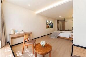 Habitación de hotel con cama, mesita de noche, silla y una pequeña mesa redonda con un jarrón de flores.