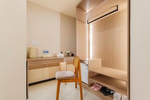 A compact kitchenette with a wooden countertop, a chair, and a built-in shelf with shoes.