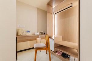 Una kitchenette compacta con encimera de madera, una silla y un estante empotrado con zapatos.