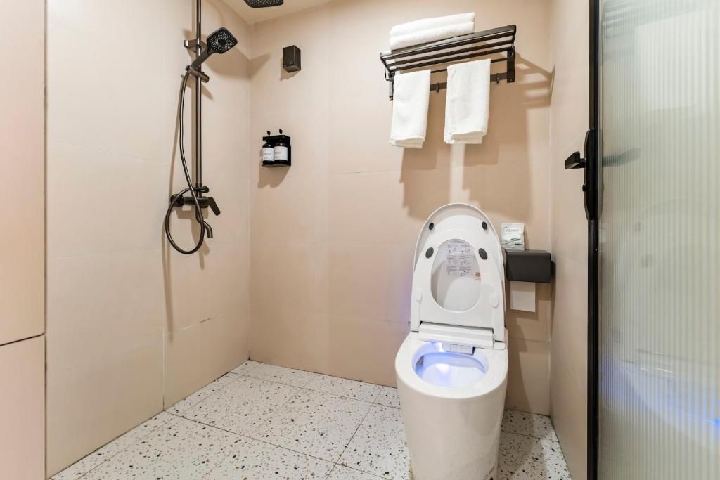 A small, private bathroom with a toilet, a shower, and a towel rack.