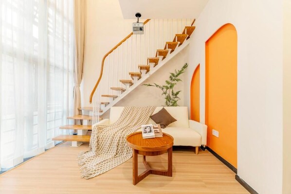 A modern living room with a staircase, a sofa, a coffee table, and a plant.