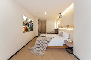 Habitación de hotel con cama, mesita de noche, teléfono y espejo.