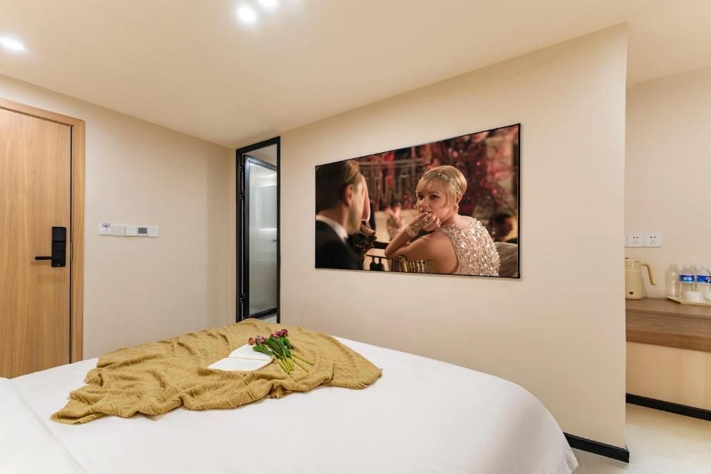 A hotel room with a bed, a television mounted on the wall, and a wooden door.
