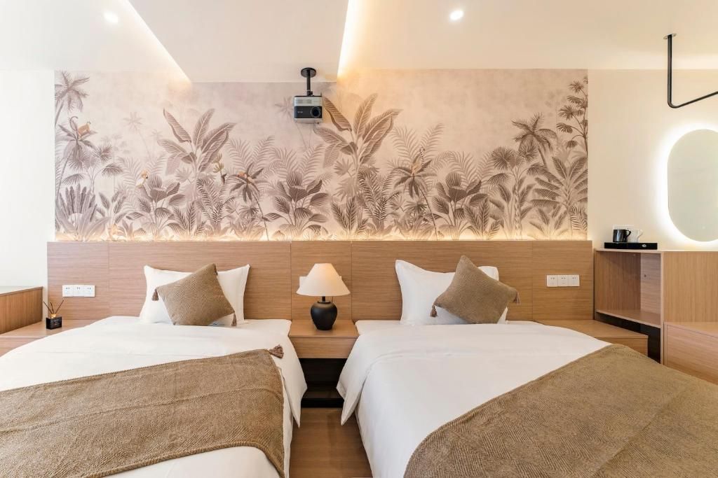 A hotel room with two beds, a wall mural, a bedside lamp, and a bedside table.