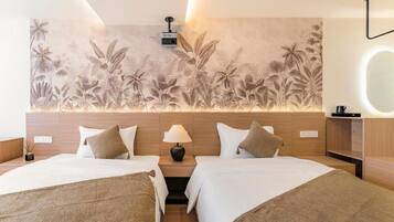 A hotel room with two beds, a wall mural, a bedside lamp, and a bedside table.