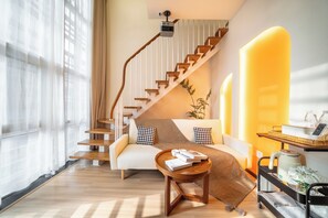 Una sala moderna con una escalera, un sofá, una mesa de centro y una planta.