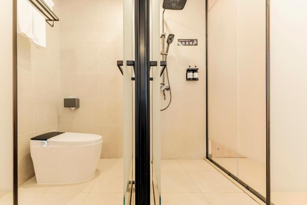 A modern bathroom with a glass-enclosed shower, a toilet, and a towel rack.