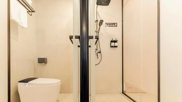A modern bathroom with a glass-enclosed shower, a toilet, and a towel rack.