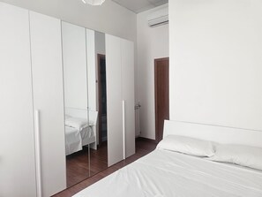 Une chambre à coucher avec un lit, une armoire avec des miroirs et un radiateur.