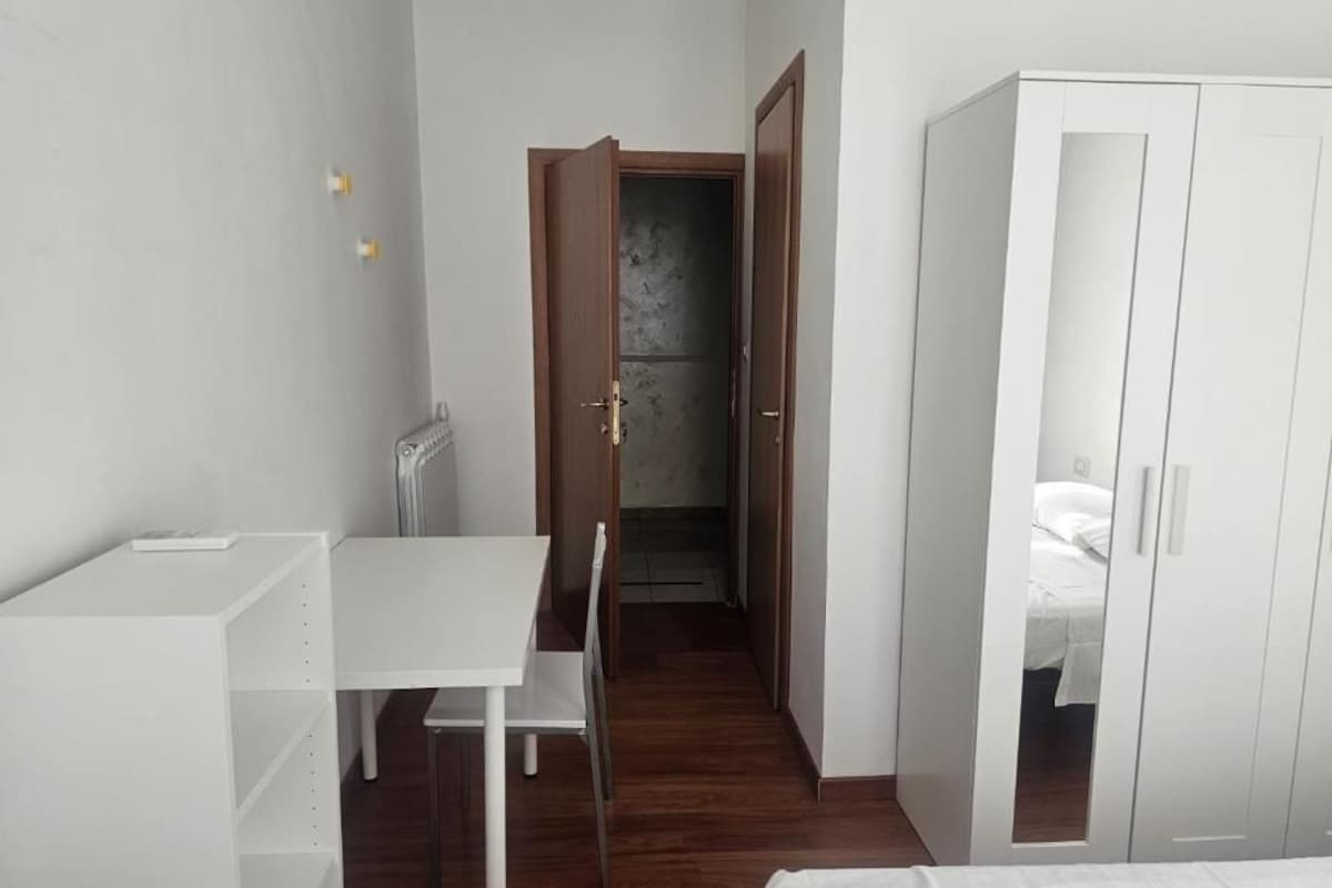 Une pièce comprenant un bureau blanc, une chaise, une armoire et une porte donnant sur une salle de bain.