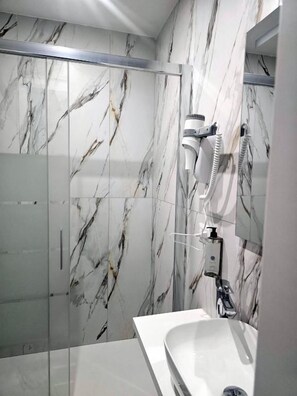 Une salle de bain avec un mur en marbre, une douche et un lavabo.