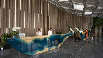 A modern reception desk with a wavy design, a high ceiling with skylights, and a vertical wooden panel wall.