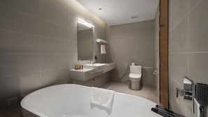 Un bagno moderno con una vasca autonoma, un mobile lavabo con specchio e un water.
