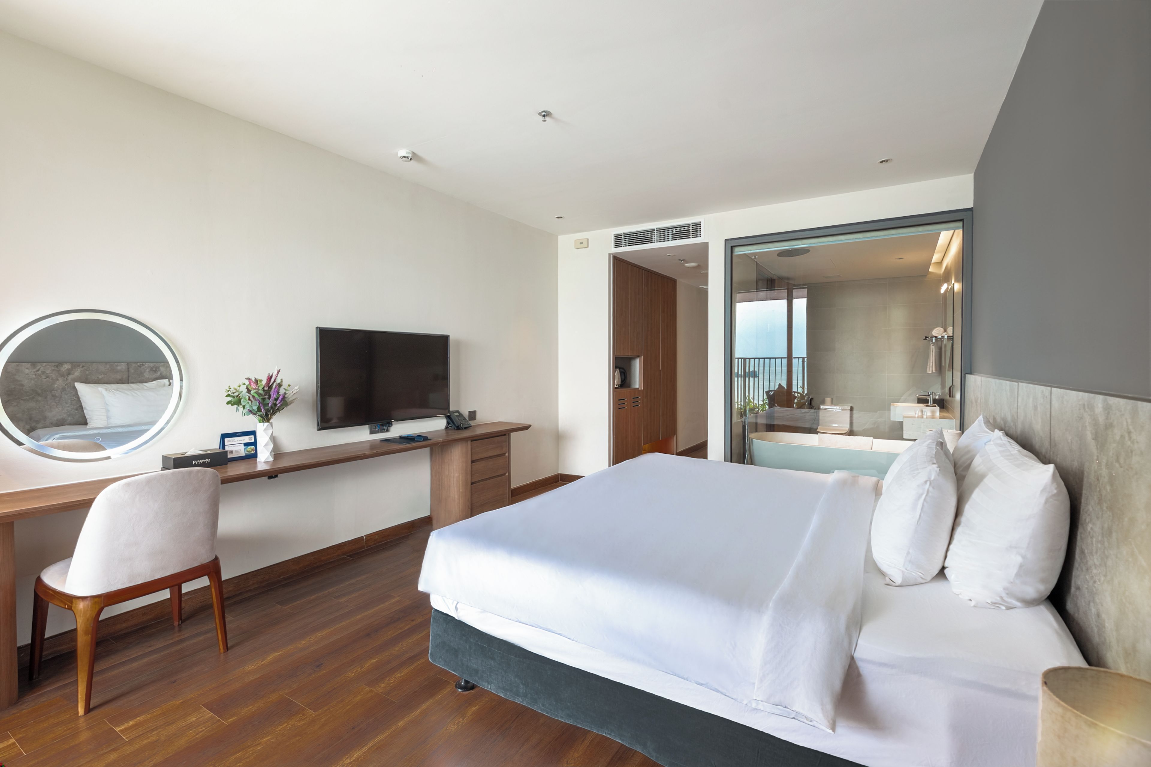 Une chambre d’hôtel équipée d’un lit, d’un bureau, d’une télévision, d’une chaise et d’un grand miroir.