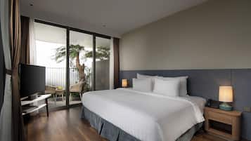 A hotel room with a bed, a TV, a desk, and a balcony with a view of palm trees.